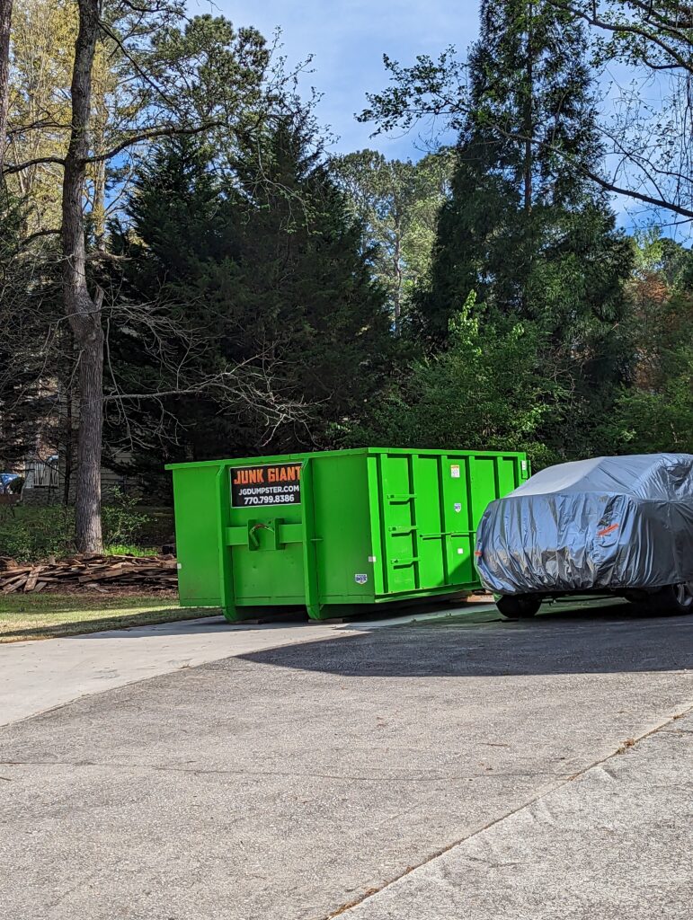 15 yard dumpster sitting next to a car on the driveway